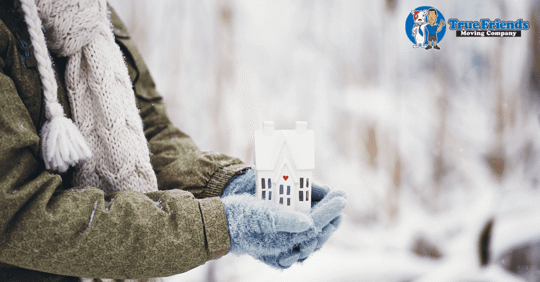 A man holding a house diorama during winter