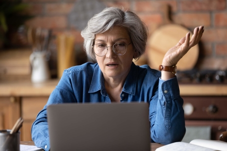 Confused middle aged woman looking at computer screen
