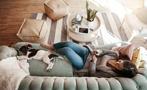 woman on phone on couch with dog